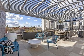 A rooftop patio with chairs and tables and a pergola